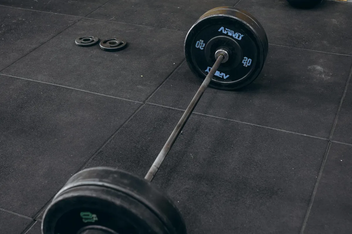 Loaded barbell and weight plates resting on the floor of an empty gym, evoking the work behind creatine supplementation