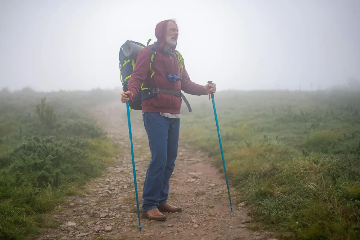 Elderly man hiking on a misty forest trail in Portugal, illustrating active ageing and strong legs