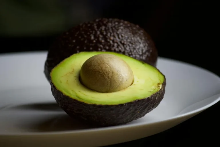 Ripe avocado halved on a plate, exposing the pit and vivid green flesh — a natural source of potassium