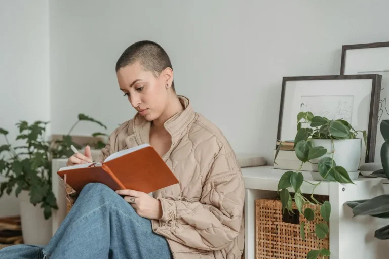 Attentive woman writing carefully in a diary at home, capturing the practice of journaling and affirmation
